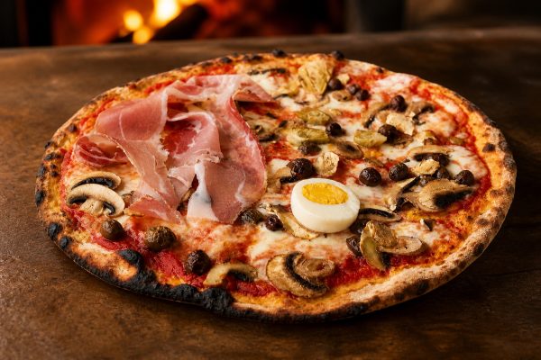 Pizza Capricciosa romana con prosciutto carciofi olive funghi e uovo